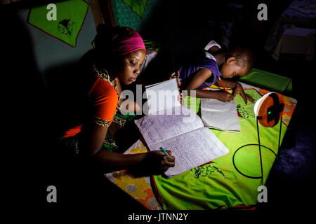 Mforo, Tanzania un villaggio nei pressi di Moshi, Tanzania. Usando un solare sorella lanterne solari diversi di energia solare di suor imprenditore Fatma Mzirayâs bambini studio durante la notte. La sua figlia Zainabu Ramadhani età19 è sul lato sinistro e sul lato medio figlia Sabrina Ramadhani, età 8 è sulla destra. Fatma Mziray è un solare sorella imprenditore che vende sia pulito e cookstoves Foto Stock