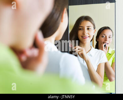 Amiche adolescenti avendo divertimento ponendo nel contempo rendere fino in prossimità dello specchio Foto Stock