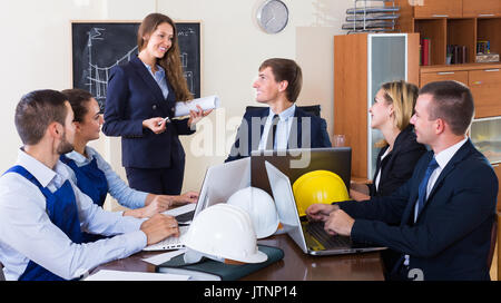 Professionisti positivo con i caschi e laptop avente riuniti in ambienti interni Foto Stock