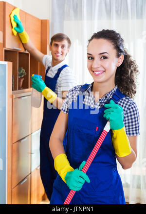 Positivo coppia giovane in uniforme sorridente e la pulizia Foto Stock