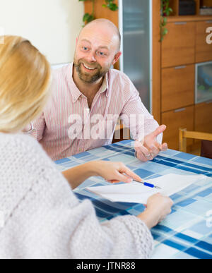 Coppia sorridente di discutere i dettagli di insediamento di matrimonio in ambienti interni Foto Stock