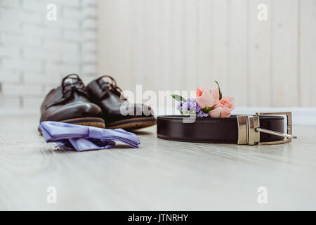 Boutonniere dello sposo di una rosa, il blu il filtro bow tie, le scarpe marrone e di una cintura per lo sposo. Foto Stock