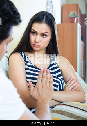 Conversazione seria tra il marito e la sua attraente giovane moglie a casa Foto Stock