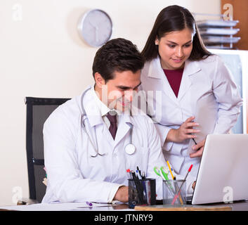 Intern chiedendo consigli da tutor medici presso la reception della clinica Foto Stock