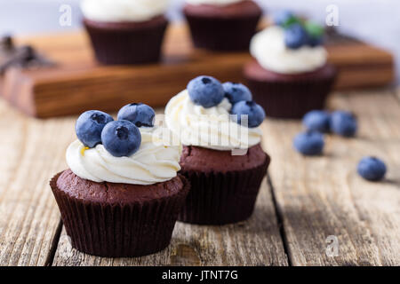 Mirtillo e crema di formaggio tortini di cioccolato sulla tavola di legno. In casa dessert estivo sul tavolo rustico Foto Stock