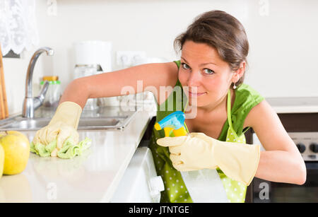 Sorridenti ragazza la pulizia dei mobili in cucina a casa Foto Stock