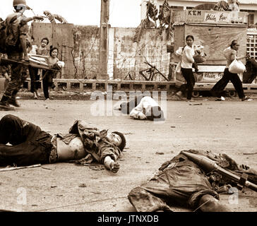 Con timore e inquietudine che mostra sulle loro facce e alla spinta del Sud soldati vietnamiti, donne e bambini caricato verso il basso con recuperati beni scurry passato i corpi dei tre Viet Cong uccisi nei combattimenti. Maggio 1968. (USIA) DATA ESATTA SHOT NARA SCONOSCIUTO FILE #: 306-MVP-4-4 guerra & conflitto prenota #: 423 Foto Stock