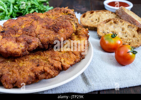 Un grande schnitzel viennesi sul legno scuro dello sfondo. Foto Stock