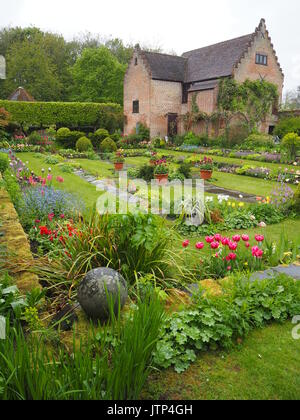 Visualizzazione verticale del Pavilion gallery a Chenies Manor sunken garden in primavera e colorati di tulipani, varietà di freschi fogliame verde e il laghetto ornamentale. Foto Stock