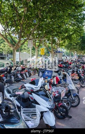 Scooter e biciclette sono popolari mezzi di trasporto in Shaghai e sono spesso visto parcheggiati sul lato se la strada o presso centri commerciali. Foto Stock