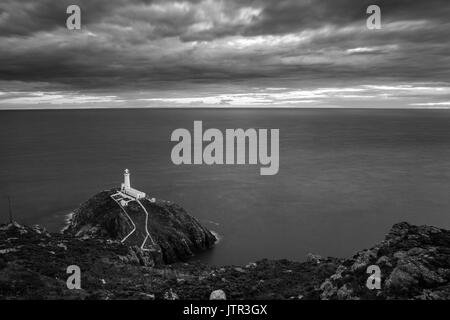 Sud pila faro, Angelsey, Wales, Regno Unito al tramonto con il sole che tramonta sull orizzonte Foto Stock