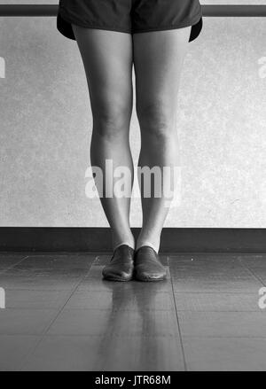 Versione in bianco e nero di gambe di una ballerina di jazz in prima posizione a barre nella classe di jazz Foto Stock