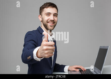 Il concetto di business - Ritratto bello uomo d affari che mostra thump fino e sorridente volto fiducioso davanti al suo computer portatile. Sfondo bianco.Copia dello spazio. Foto Stock