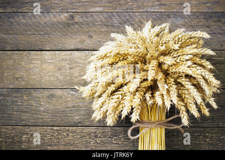 Spighe di grano sul tavolo di legno. Un covone di grano su uno sfondo di legno. Concetto di raccolto Foto Stock