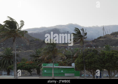 Una nebbia e ventoso paesaggio di Tenerife montagne visto dalla spiaggia di Las Teresitas al tramonto Foto Stock