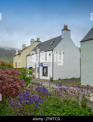 Dipinto di bianco di negozio del villaggio e adiacente casa con fiori colorati in primo piano a Dornie, Scozia Foto Stock