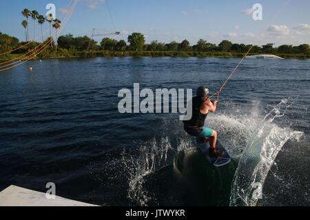 Giovane donna di essere lanciato tirato dal cavo sul Wakeboard nel lago Foto Stock