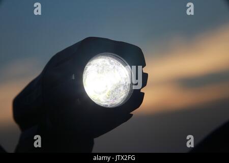 Luce per biciclette illuminata sul manubrio contro il tramonto Foto Stock