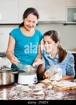 Due felici donne cottura delle patate con vaporizzatore elettrico a casa cucina Foto Stock