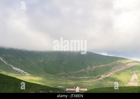 Pascolo con arieti e pecore sulla montagna presso la strada con le automobili in Georgia in una nebbiosa sfondo cielo. Foto Stock