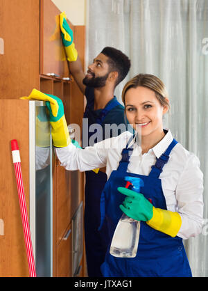 Professional sorridente giovani i detergenti per la pulizia e la spolvero in assemblea ordinaria Foto Stock