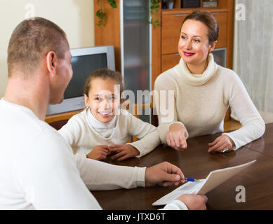 Padre e figlia sorridenti a rispondere a domande di outreach lavoratore a casa Foto Stock