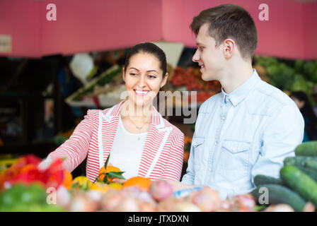 Coppia giovane acquistare frutta e verdura in mercato e sorridente Foto Stock