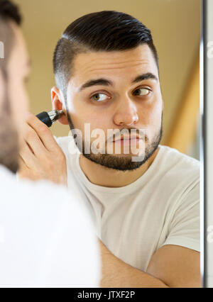 Ritratto uomo bello rivestimenti naso e orecchie capelli a casa Foto Stock