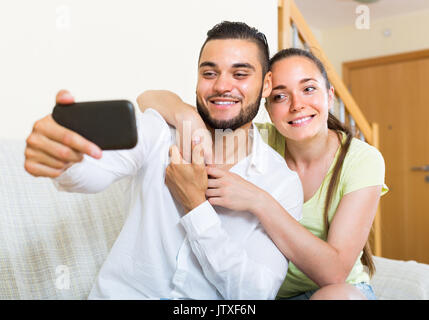 Uomo sorridente e la donna posa per una selfie a casa Foto Stock