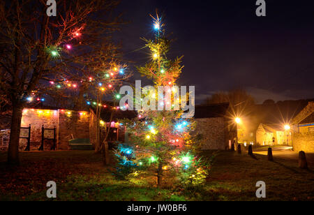 Albero di natale e luci festose impreziosiscono il villaggio verde in Eyam, un villaggio storico nel Peak District, Derbyshire,l'Inghilterra,UK - Dicembre Foto Stock