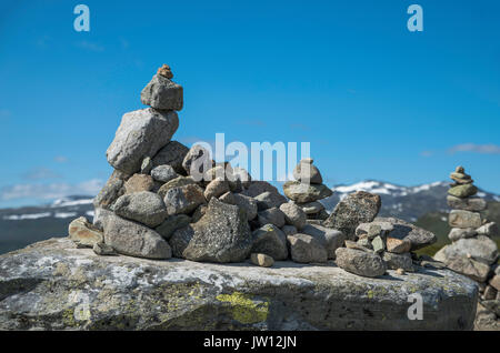 Stack equilibrata di pietre a Eidfjorden, Norvegia con la neve e le montagne come sfondo Foto Stock