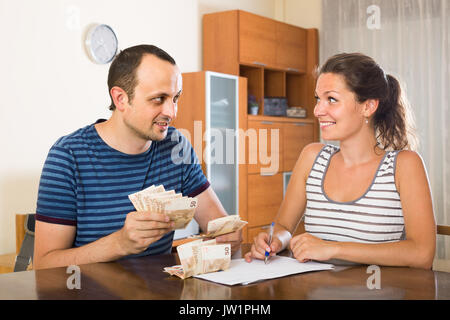 Donna adulta guardando suo marito conteggiare denaro Foto Stock