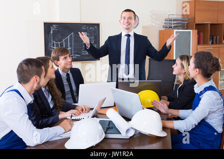 Ritratto di professionisti con caschi e computer portatili aventi riuniti in ambienti interni Foto Stock