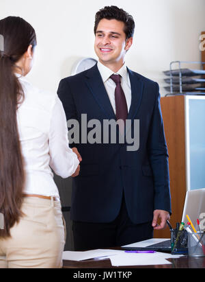 Manager di nuovo il messaggio di saluto dei dipendenti europei e sorridente in ufficio Foto Stock