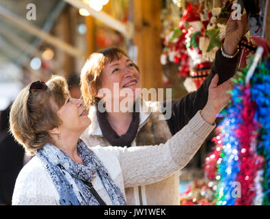 Allegro donne mature camminando sul mercato di Natale e la scelta di gioielli Foto Stock