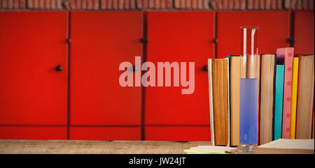 Libri disposti su un tavolo di legno contro di close-up di armadietti arancione Foto Stock