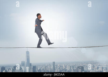 Imprenditore di eseguire un bilanciamento atto contro il balcone che si affaccia sulla città Foto Stock