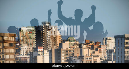 Silhouetters celebrando contro la luce solare che rientrano su edifici contro sky Foto Stock