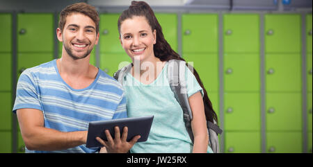 Gli studenti che usano tablet e sorridente contro Locker room Foto Stock