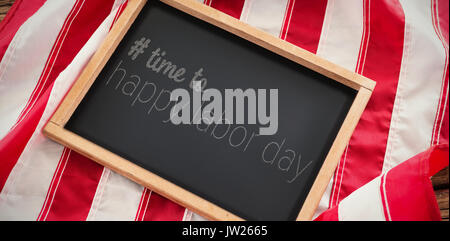 Digital immagine composita del tempo di felice Festa del lavoro testo contro la bandiera americana con l'ardesia sul tavolo di legno Foto Stock