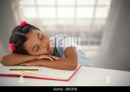 Ragazza sonnecchiare sul libro al banco contro la camera con grande finestra che mostra città Foto Stock