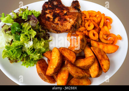 Tritare la carne di maiale in mollica di pane servito con patate arrosto e insalata lattuga su una piastra bianca. Foto Stock