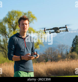 Giovane uomo controllo battenti quadrocopter telecomandato drone con fotocamera, DJI Mavic Foto Stock