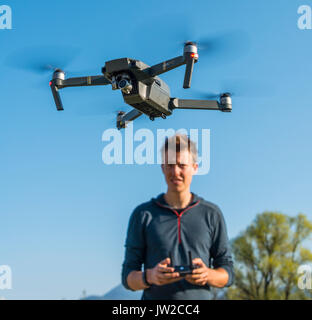 Giovane uomo controllo battenti quadrocopter telecomandato drone con fotocamera, DJI Mavic Foto Stock
