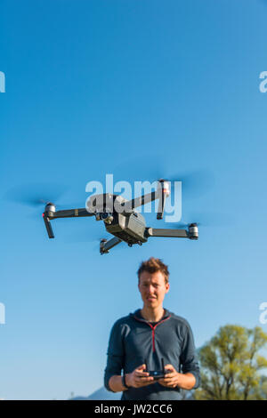 Giovane uomo controllo battenti quadrocopter telecomandato drone con fotocamera, DJI Mavic Foto Stock