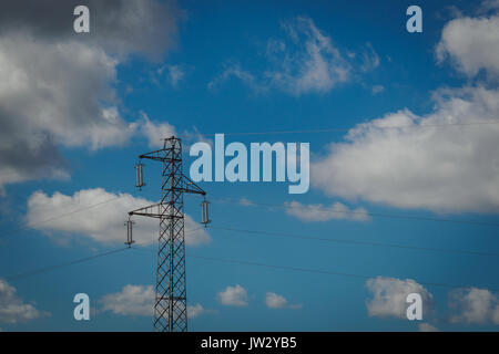 Traliccio elettrico con un nuvoloso cielo blu in background. Foto Stock