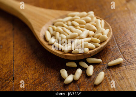 Cucchiaio di legno pieno di pinoli su tavola Foto Stock