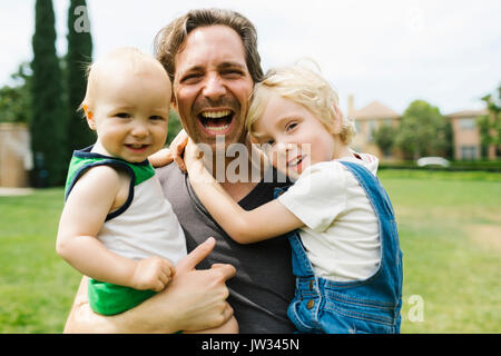 Ritratto di padre che trasportano figli (12-17 mesi, 4-5) in posizione di parcheggio Foto Stock