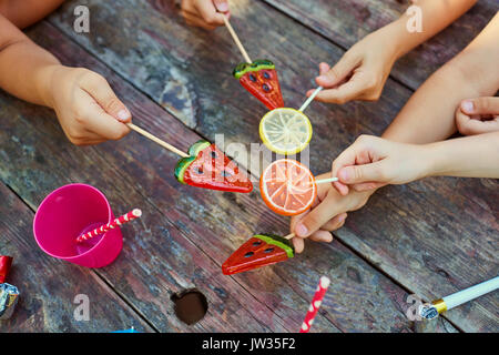 Mani di bambini con dolci su uno sfondo di legno. Foto Stock