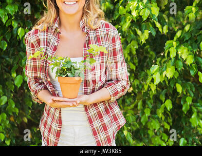 Donna sorridente azienda pianta in vaso Foto Stock